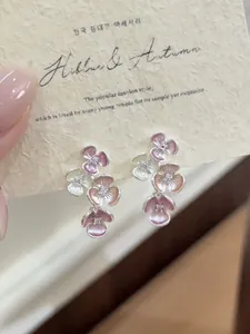 Close-up view of pink enamel flower stud earrings with sparkling rhinestone centers