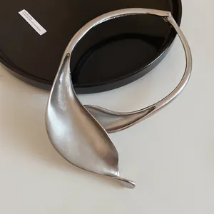 Dettaglio del girocollo metallico argento opaco con design minimalista a forma di petalo