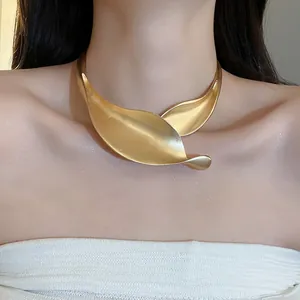 Dettaglio ravvicinato di un girocollo minimalista in metallo foglia oro opaco sul collo
