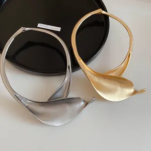 Dettaglio dei girocollo in metallo opaco oro e argento con design a petalo artistico.