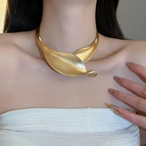 Primo piano di una collana choker minimalista in metallo oro opaco a forma di foglia su modella