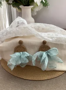 Vista dettagliata della trama di rafia e del pendente in chiffon azzurro di questi orecchini boho