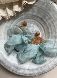 Primo piano di orecchini da spiaggia con fiocchi in chiffon azzurro e rafia intrecciata