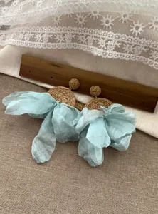 Dettaglio di orecchini in rafia stile spiaggia con grandi fiocchi in chiffon azzurro