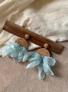 Dettaglio di orecchini in rafia intrecciata con goccia in chiffon azzurro mare