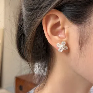 Close-up detail of elegant silver four-petal flower stud earrings with sparkling zircon stones
