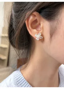 Detailed view of elegant silver four-leaf flower stud earrings with clear zircons on ear
