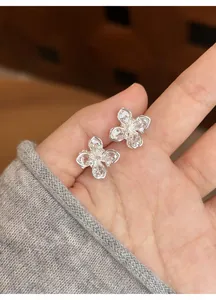 Detail view of these silver-toned flower stud earrings with shimmering zircon stones