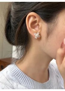 Close-up detail of a silver zircon four-leaf flower stud earring worn by an Asian model