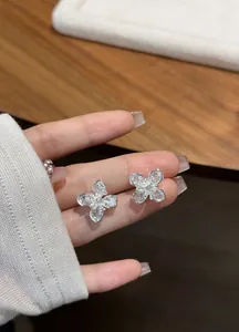Detail of sparkling silver four-leaf flower stud earrings with clear zircon stones.