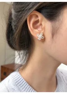 Close-up view of silver clover earrings with zircon stones worn by an Asian model