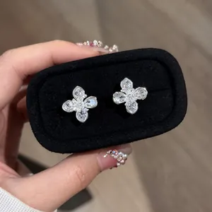 Close-up of elegant silver four-leaf flower stud earrings set with clear zircons