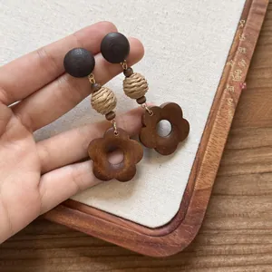 Dettaglio macro di orecchini a fiore in legno fatti a mano con sfere di paglia intrecciata