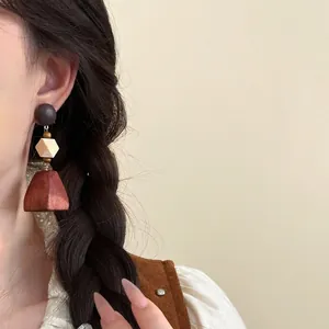Primo piano di orecchini geometrici in legno in stile etnico indossati da modella