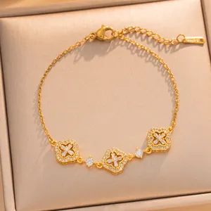 Detailed view of a gold-tone bracelet featuring sparkling clover charms and clear stones.