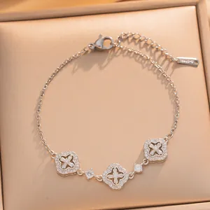 Macro view of an elegant gold-plated bracelet featuring three sparkling crystal clover charms