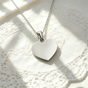 Close-up of polished stainless steel heart pendant on silver chain necklace