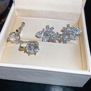 Close-up detail of sparkling zircon flower and leaf earrings inside a white jewelry box