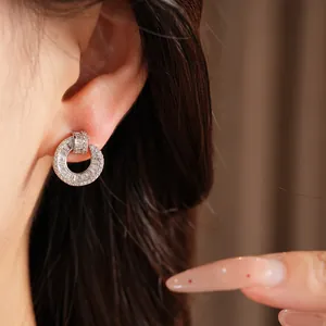 Detailed view of silver-toned round stud earrings encrusted with sparkling zircons