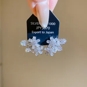 Detailed close-up of sparkling flower and leaf zirconia stud earrings with silver needles