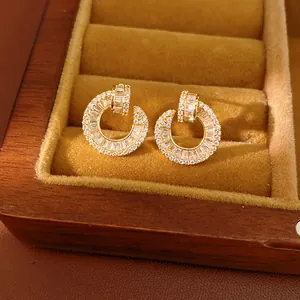 Detailed view of gold-plated circular earrings with sparkling cubic zirconia in a box.