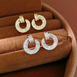 Detail shot of circular zircon-encrusted earrings in 18k gold and silver finish