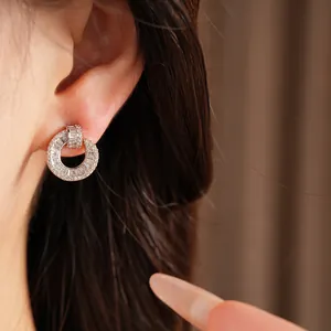 Macro view of minimalist 18k gold plated circular stud earrings with baguette zircons