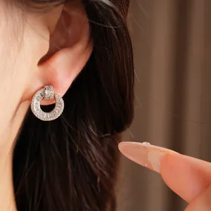 Close-up of circular CZ stud earrings on model's ear showing delicate sparkle