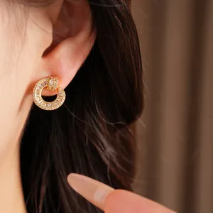 Close-up of 18k gold plated circular stud earrings with sparkling zircon inlay.