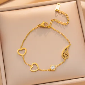 Detailweergave van vergulde titanium stalen armband met hart- en vleugelbedels.