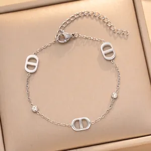Vue rapprochée d'un bracelet en acier titane argenté avec des breloques en lettre D