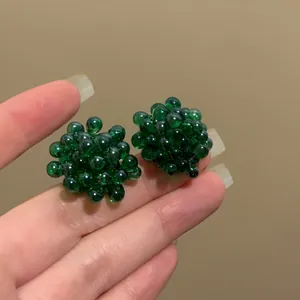Vista detallada de pendientes de racimo con cuentas verde oscuro y diseño de uva único.