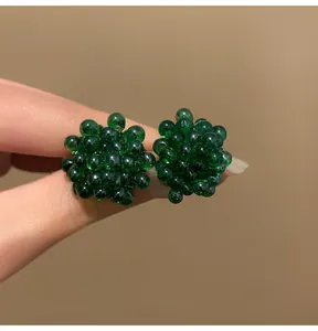 Vista ravvicinata di orecchini unici a forma di grappolo verde scuro con perline traslucide.