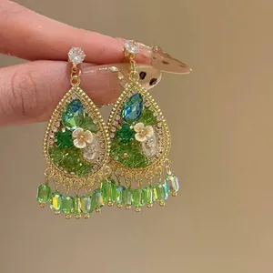 Close-up detail of vintage water drop earrings with green crystals and floral accents