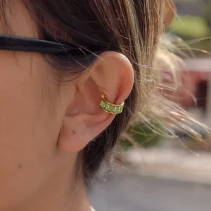 Detail view of a gold-plated stainless steel ear cuff with green rectangular zircons