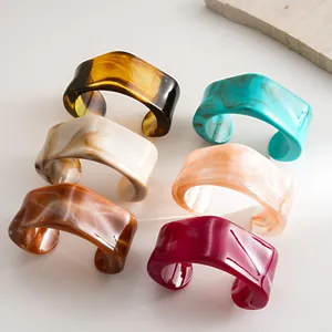 Detail showing various colors of irregular geometric acrylic cuff bracelets with marble patterns