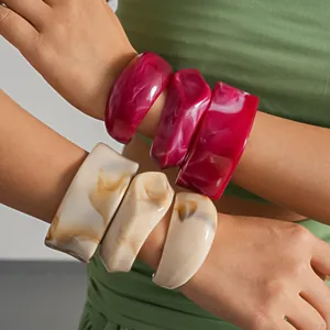 Close-up of stacked irregular geometric acrylic bangles with marble texture in magenta and cream