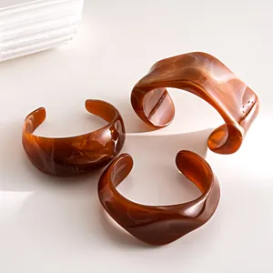 Detailed macro shot of three amber-toned acrylic cuff bracelets featuring marble swirl textures