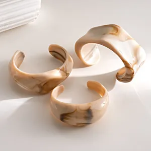 Set of three minimalist irregular acrylic cuff bracelets featuring beige marble swirl pattern