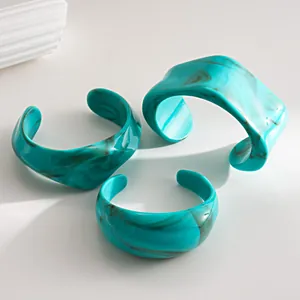 Detailed view of three turquoise marbled acrylic bangles with irregular geometric shapes.