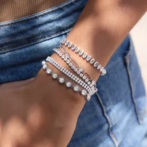 Detailed view of luxury silver-toned tennis and paperclip link bracelets set on a female wrist
