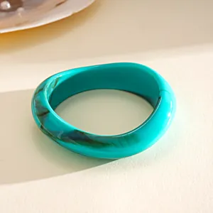 Dettaglio macro di un bracciale in acrilico marmorizzato turchese con geometria