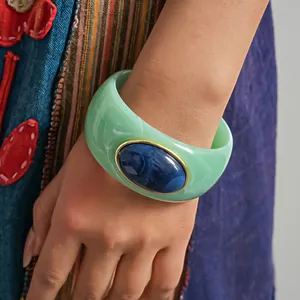 Dettaglio di un bracciale in acrilico marmorizzato verde menta con pietra in resina blu.