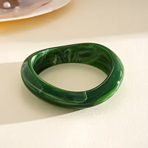 Dettaglio di un bracciale in acrilico marmorizzato verde scuro con forma irregolare