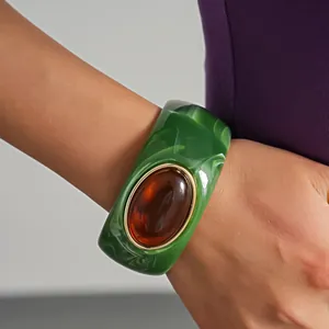 Dettaglio di un bracciale in acrilico marmorizzato verde con intarsio in resina