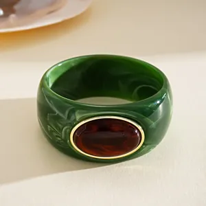 Vista dettagliata di un bracciale rigido in acrilico verde con resina marrone