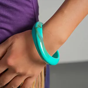 Dettaglio ravvicinato della trama marmorizzata di un bracciale rigido in acrilico turchese
