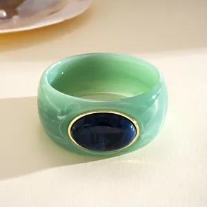 Vista macro di un bracciale in acrilico marmorizzato verde con pietra ovale blu scuro