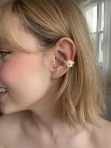 Primo piano di ear cuff a fiori margherita, gioiello orecchio senza buco per donna