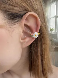 Primo piano di un ear cuff a margherita bianca indossato su un orecchio senza buco.
